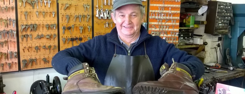 Steve Knight, Cobbler holding boots, comparing repaired and broken, background rows of uncut keys